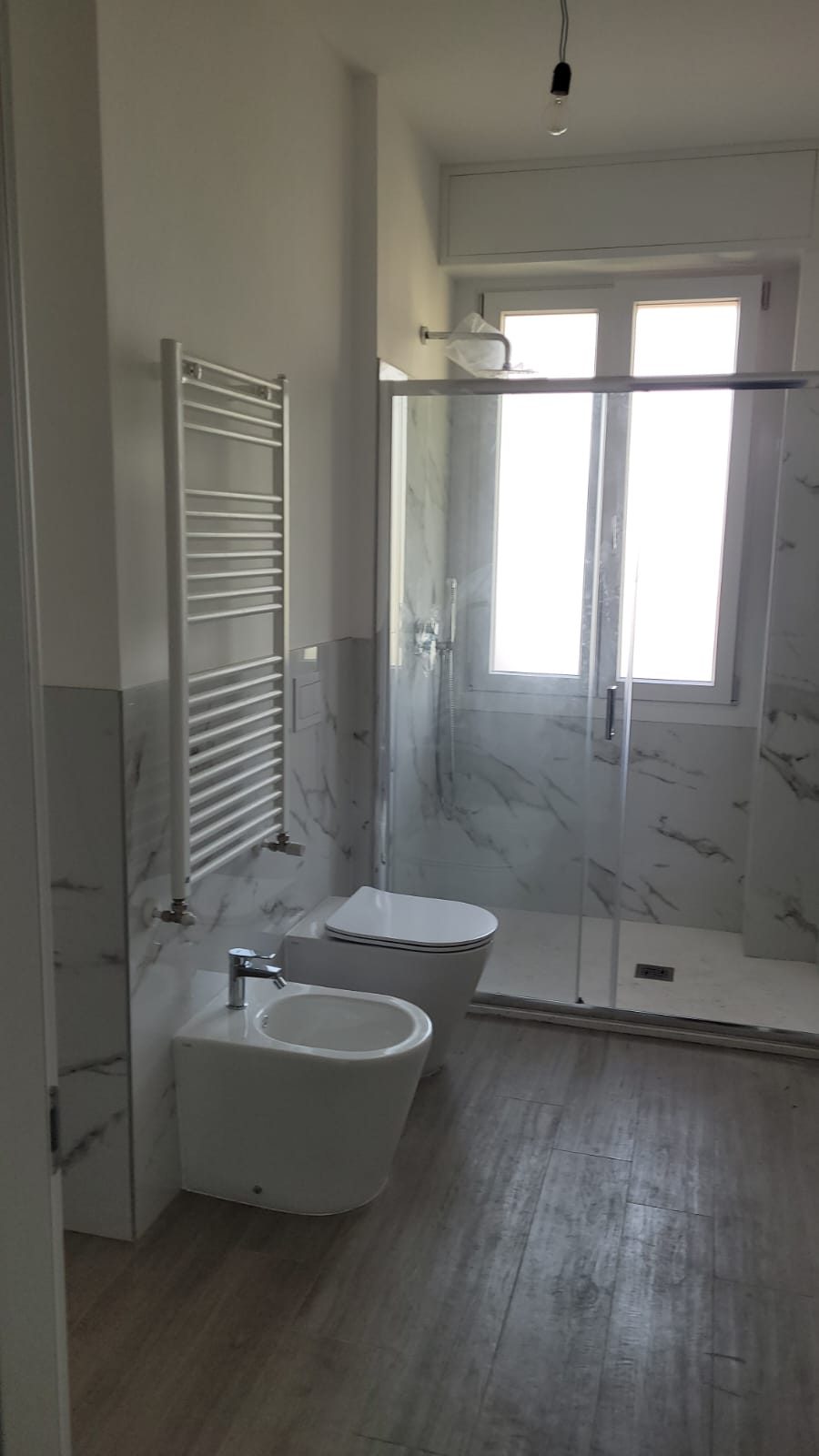 Bagno finito con doccia a filo pavimento e rivestimento in gres effetto marmo
